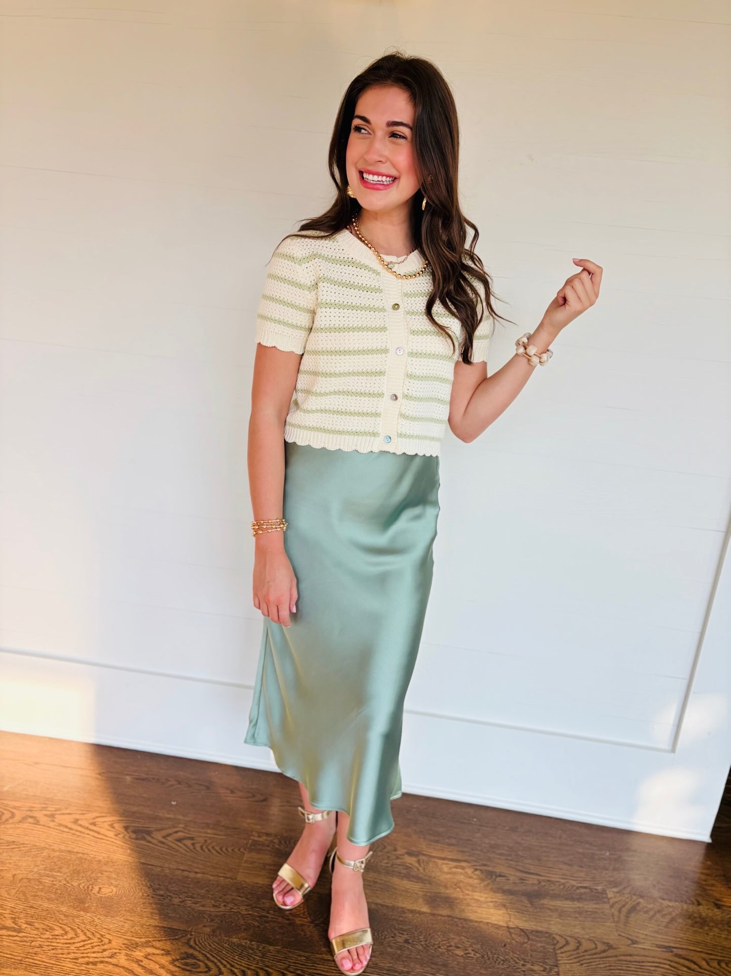 Lacey wearing the Kenzie sage green striped short-sleeve knit cardigan with a satin midi skirt