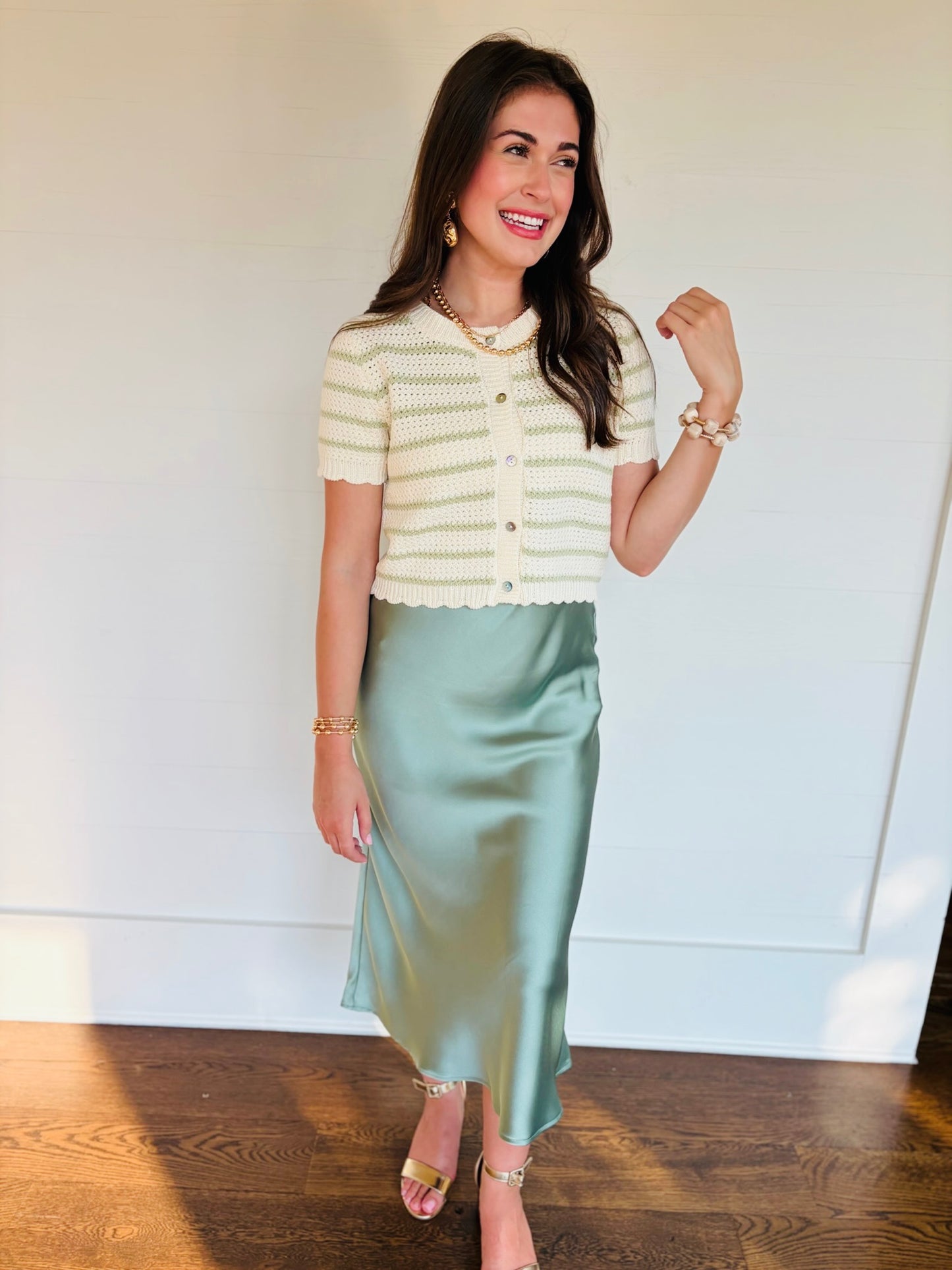 Full-length view of Lacey styling the Kenzie sage green striped knit cardigan with a sage satin midi skirt