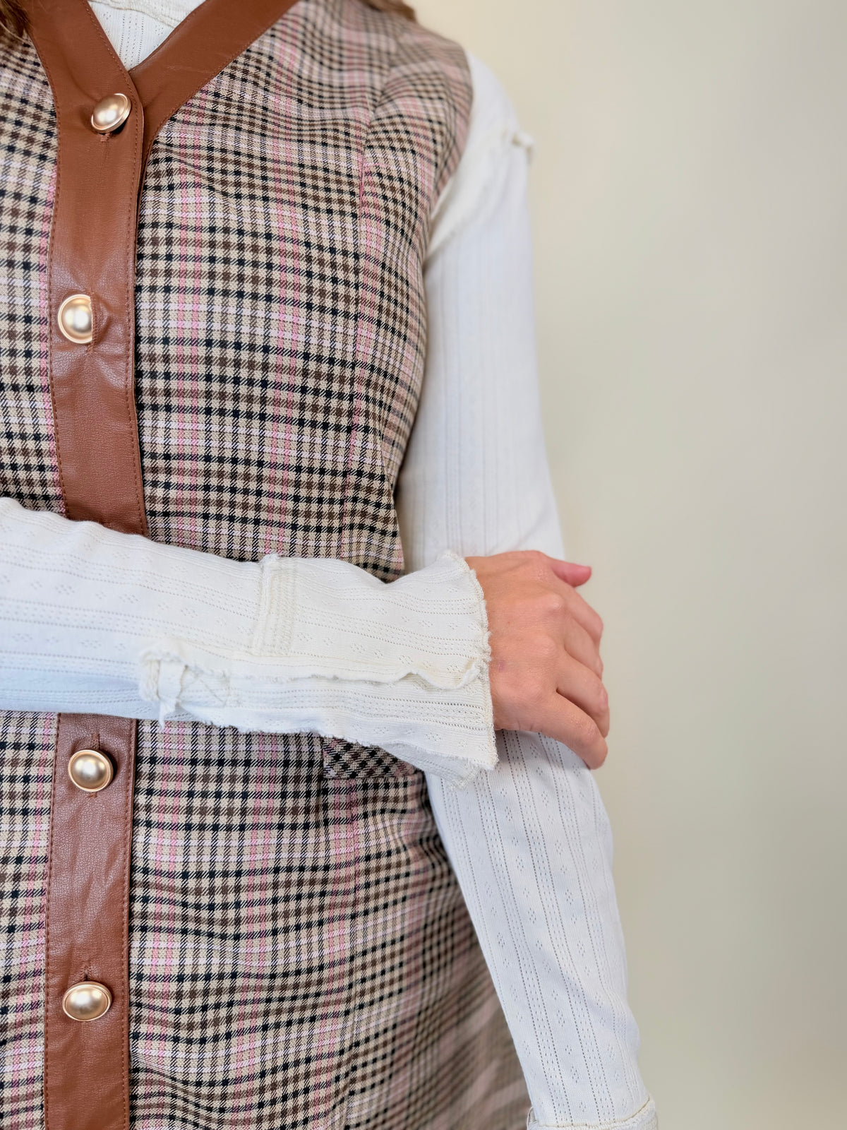 Close-up of the Kinsley ecru layering top showing its pointelle sleeve texture and ruffled cuff beneath a plaid vest dress.