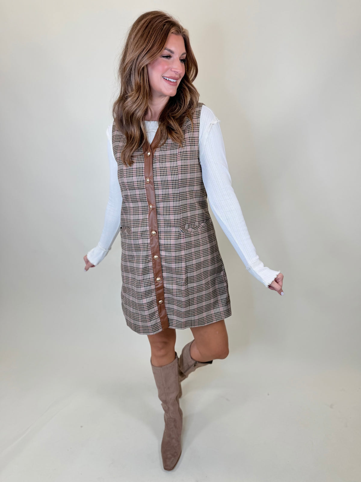 Morgan wearing the Kinsley ecru pointelle layering top beneath a plaid vest dress with neutral knee-high boots.