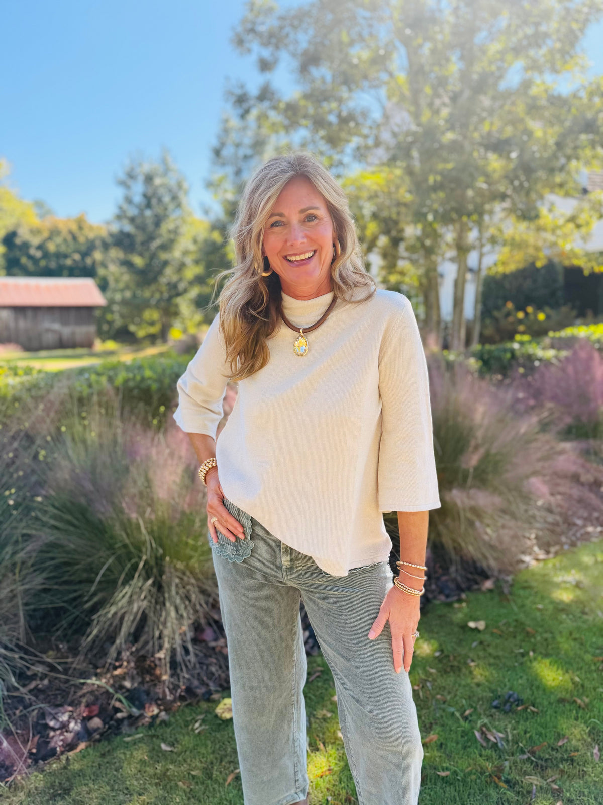 Kelly wearing the Lenora ecru top, showing its textured fabric, mock neckline and gently flared three-quarter sleeves.