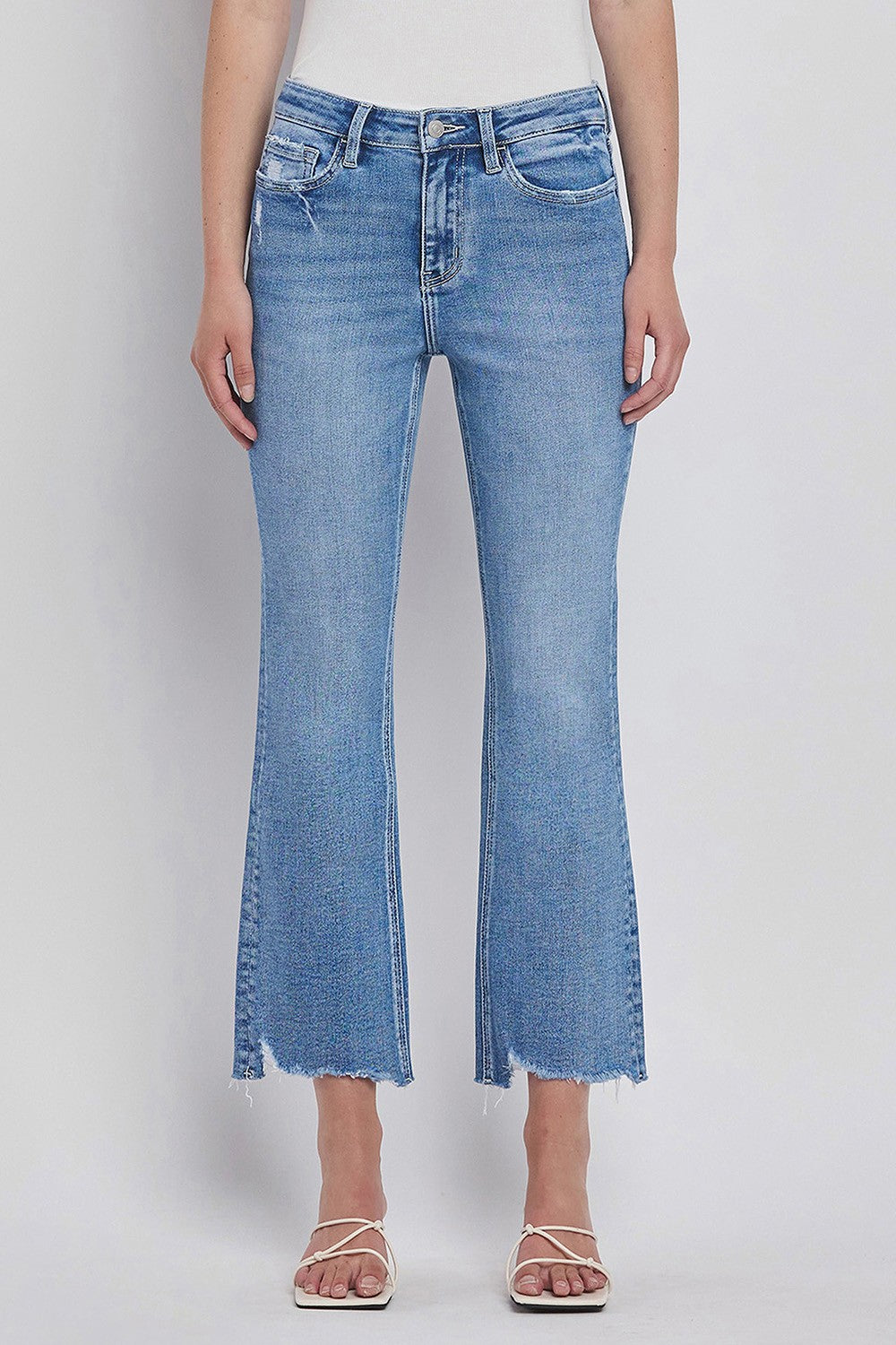 Light blue denim cropped flare jeans with frayed hem, worn with strappy nude sandals