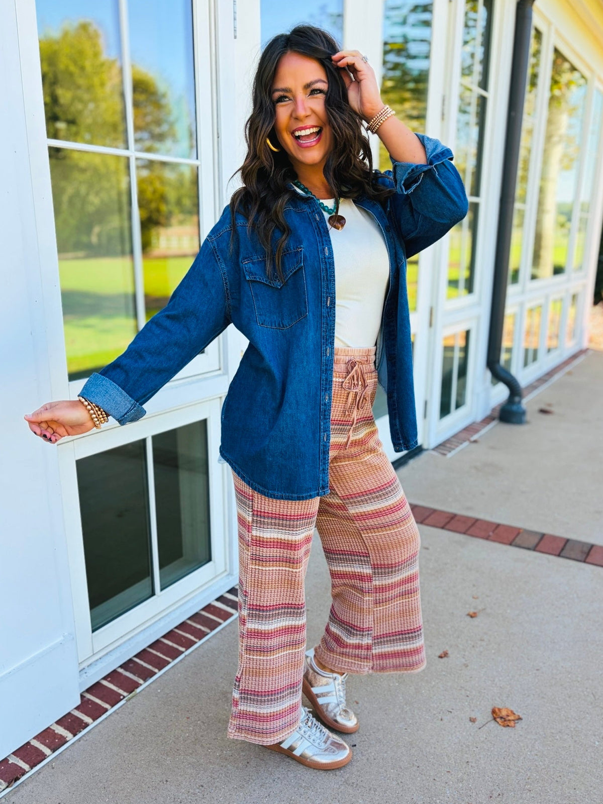 Brooke wearing the Margaret dark wash denim shirt jacket over a cream top with multicolor wide-leg pants.
