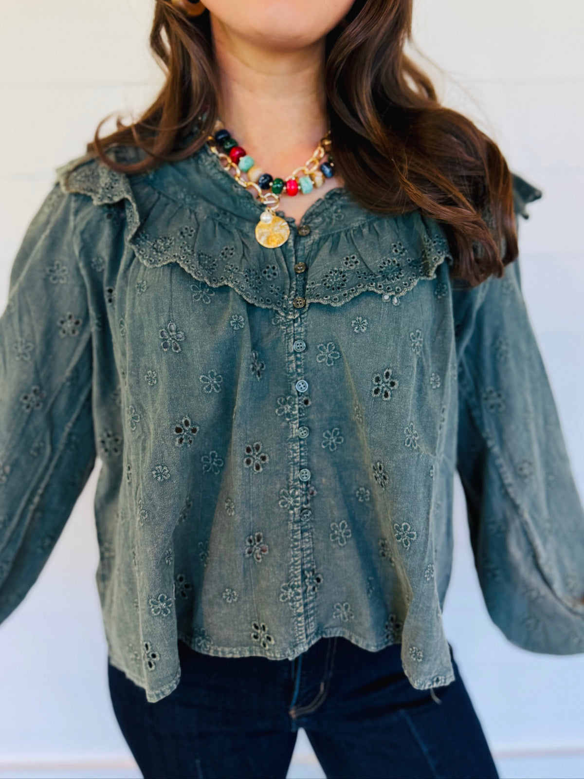 Close-up of the Mariana moss blouse showing its floral eyelet embroidery, ruffle-trimmed yoke and button front.