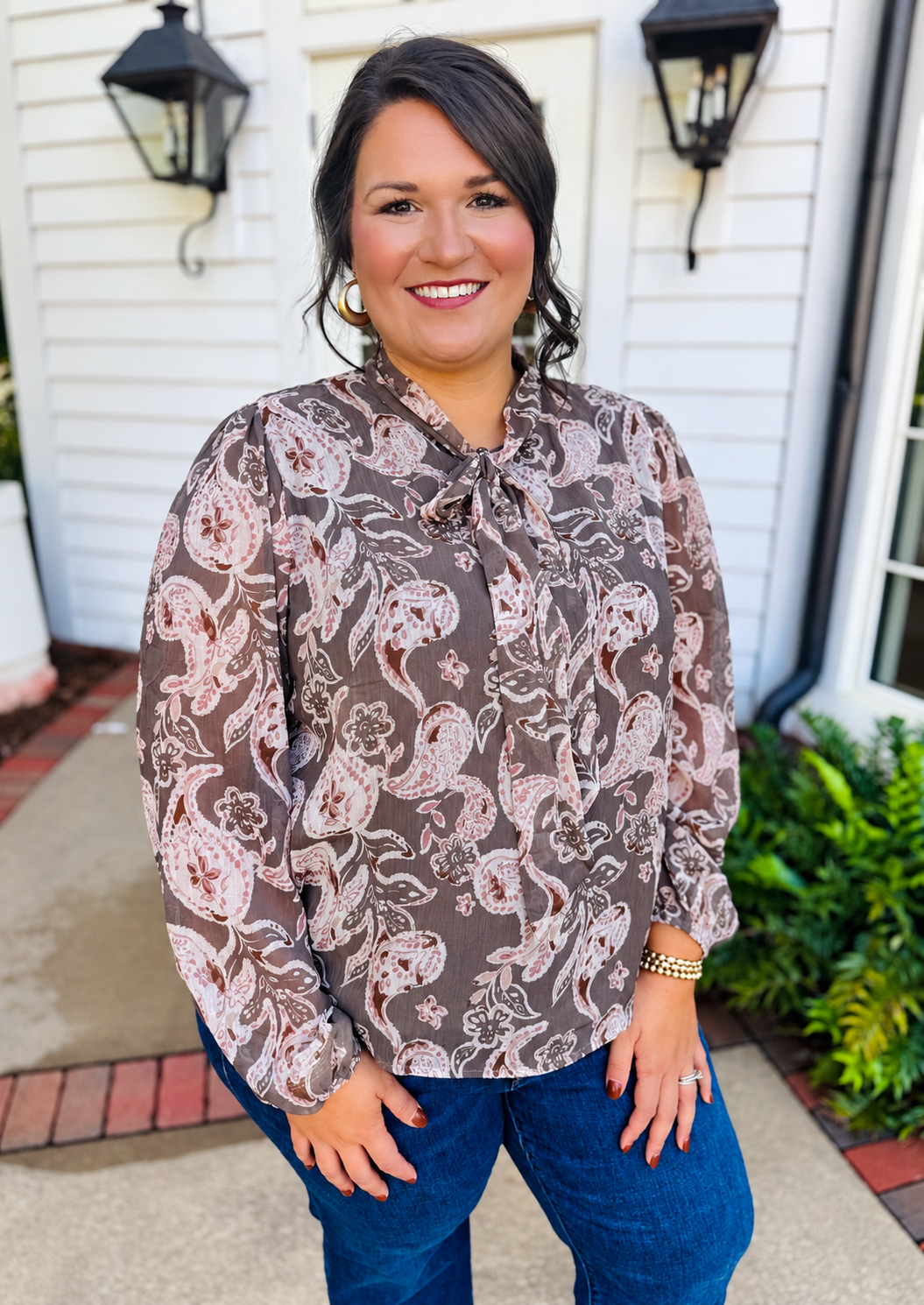 Alex wearing the Maribel light olive paisley tie-neck blouse with blue jeans.