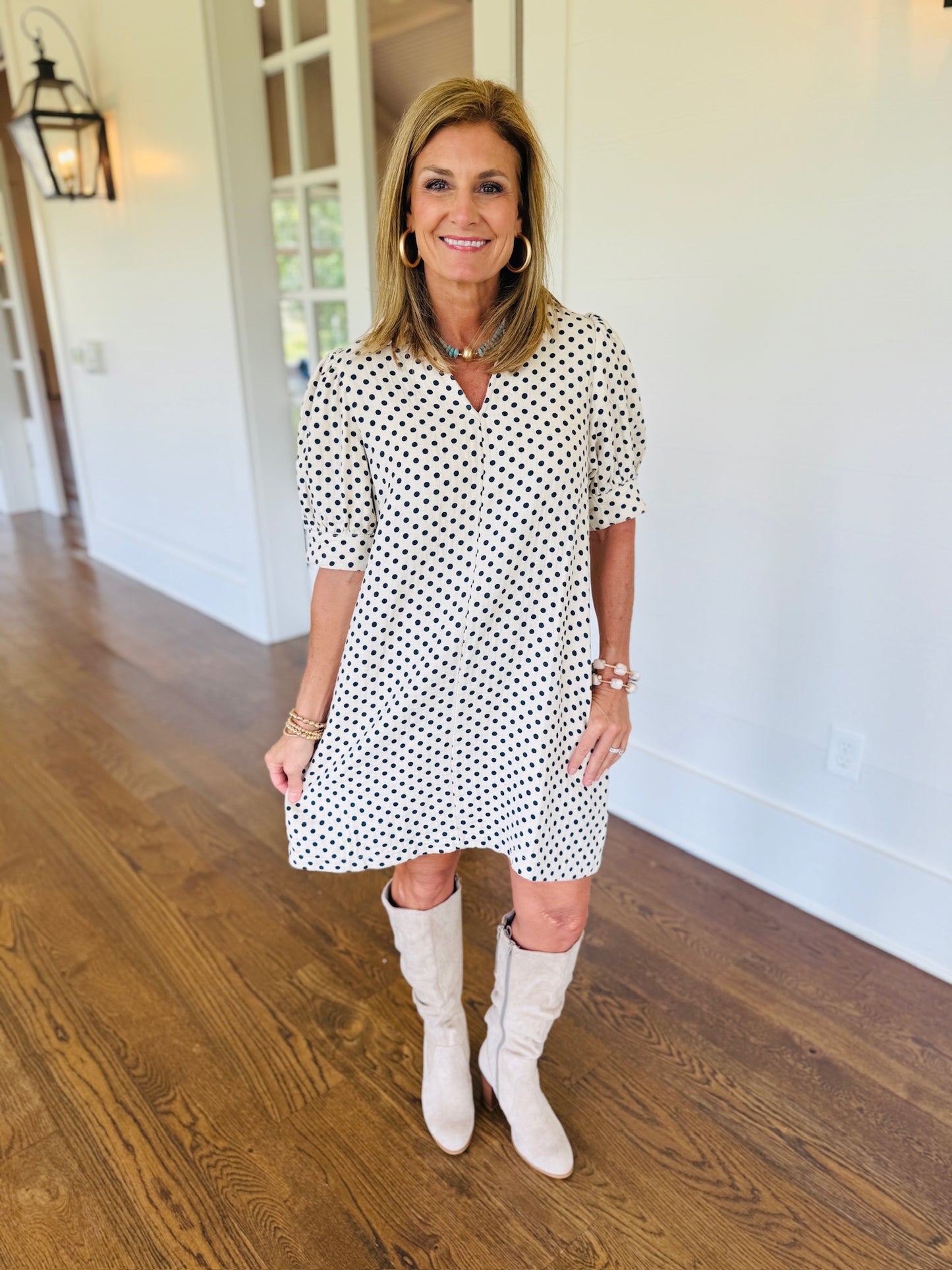 Ginny wearing the Marlee cream and navy polka-dot mini dress with tall cream boots