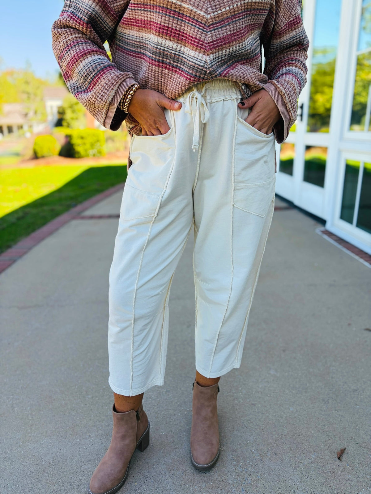 Close-up of the Marlowe ecru barrel pants showing their drawstring elastic waistband, oversized patch pockets and exposed seam details.