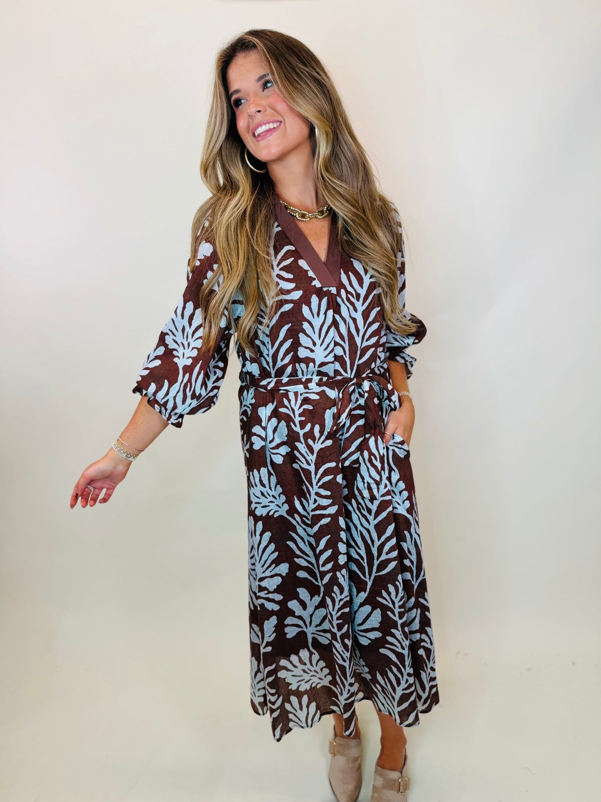 Mason brown and light blue botanical midi dress, showing the tie waist and side pocket on the model.