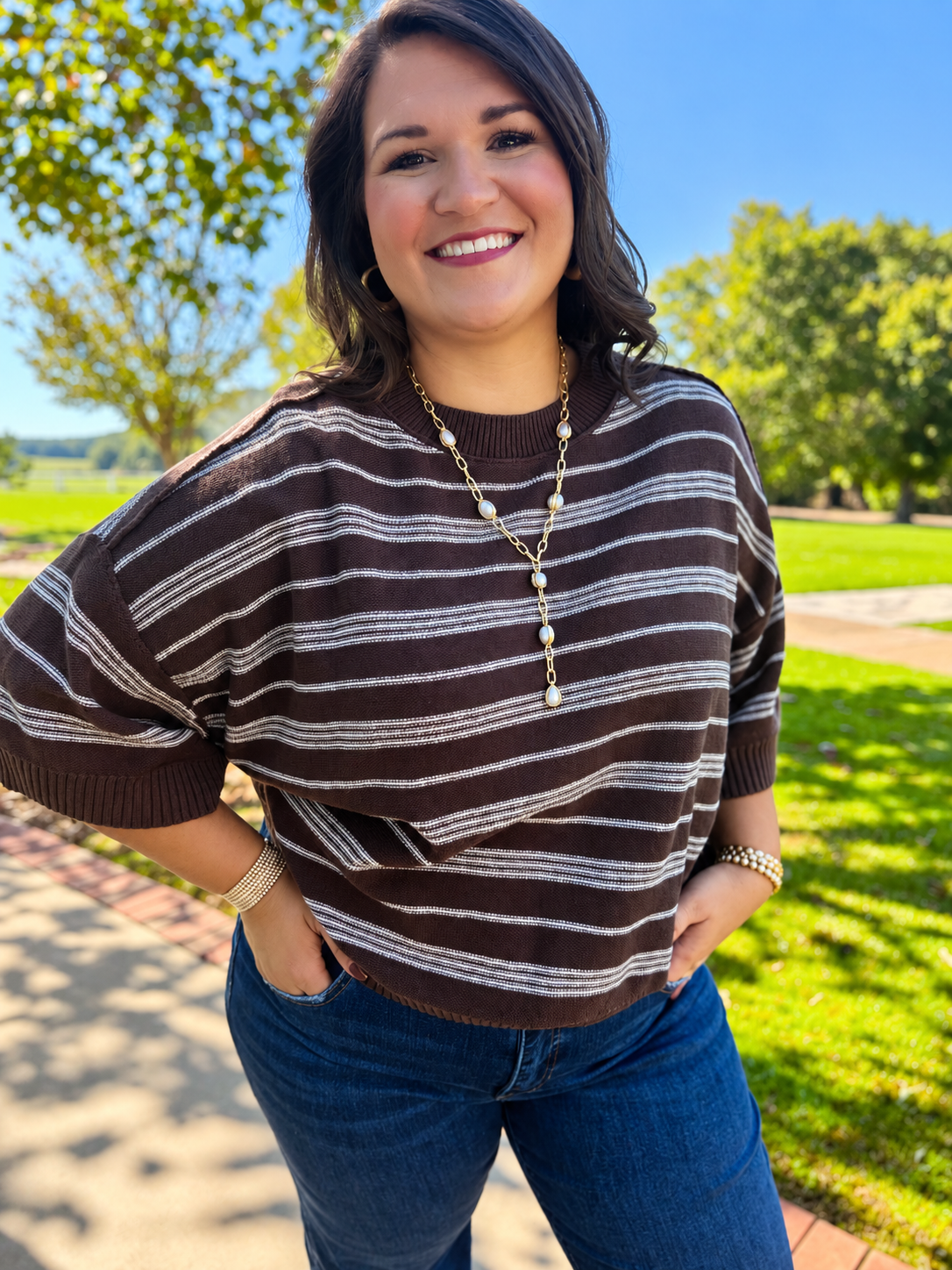 Close-up of the Melly brown striped sweater showing its crew neckline, short dolman sleeves and ribbed trim.