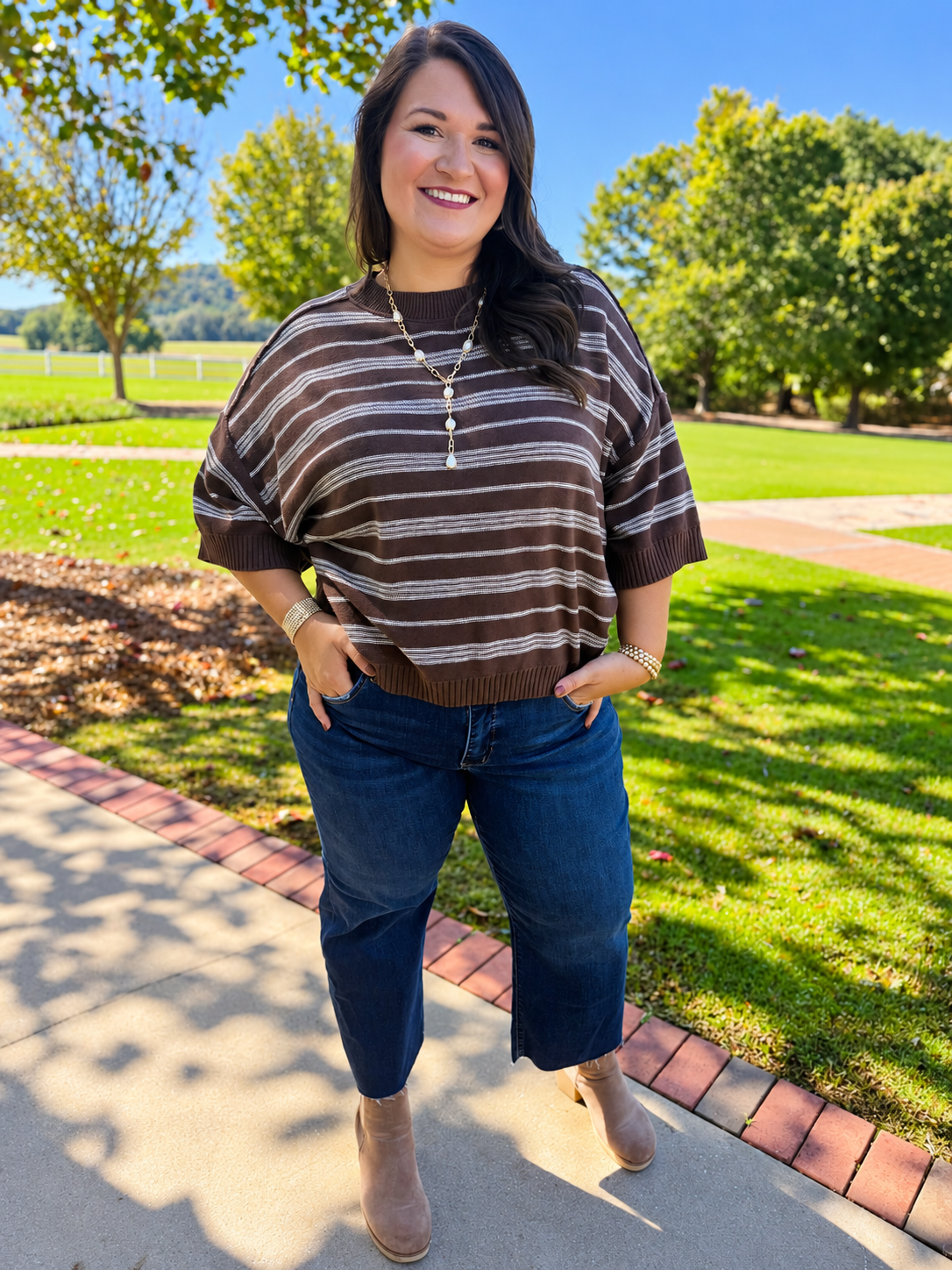 Alex wearing the Melly brown striped short-sleeve sweater with cropped blue jeans and neutral ankle boots.