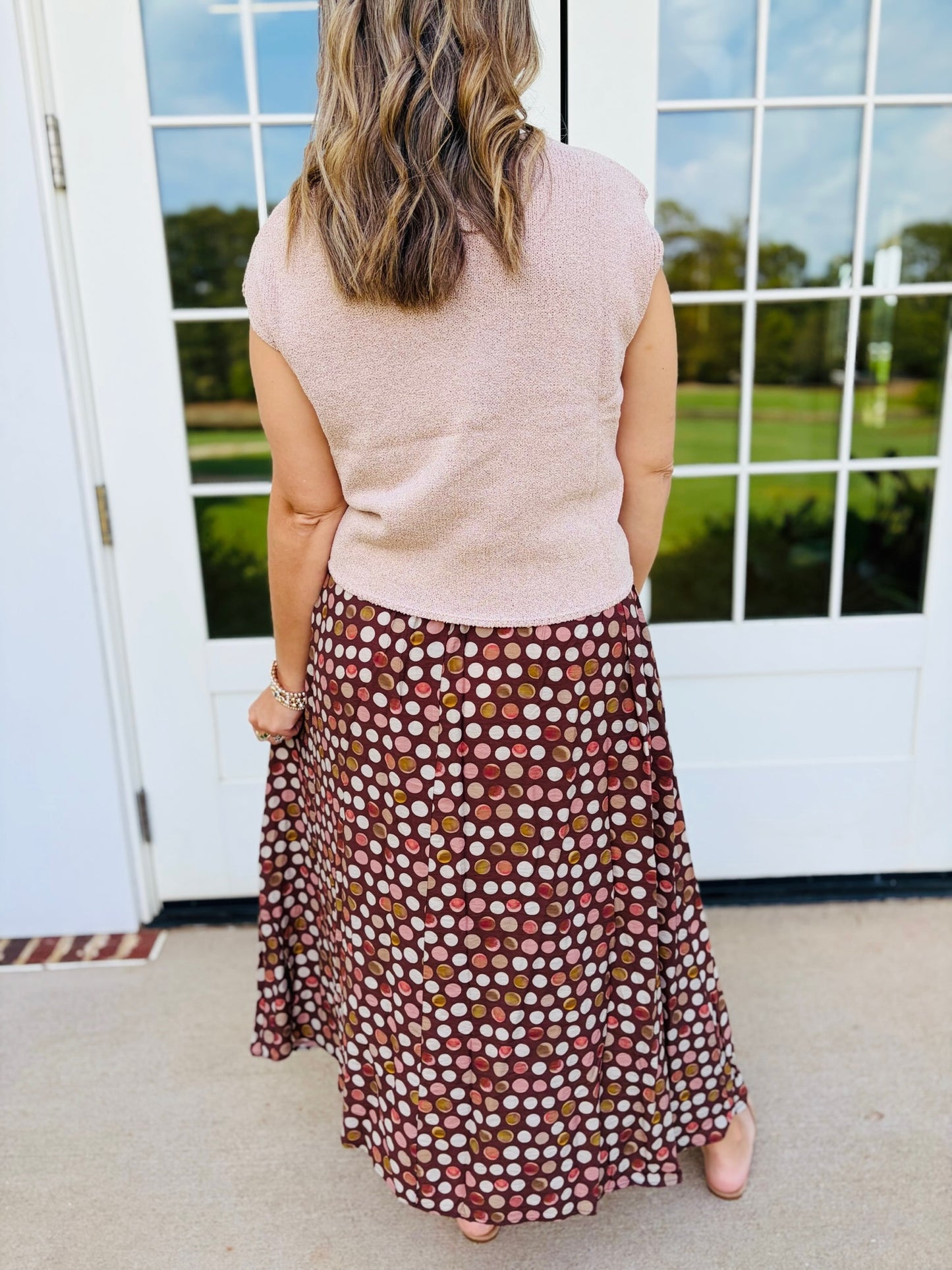 Back view of Jessica wearing the Millie brown multicolor polka-dot maxi skirt with a blush top