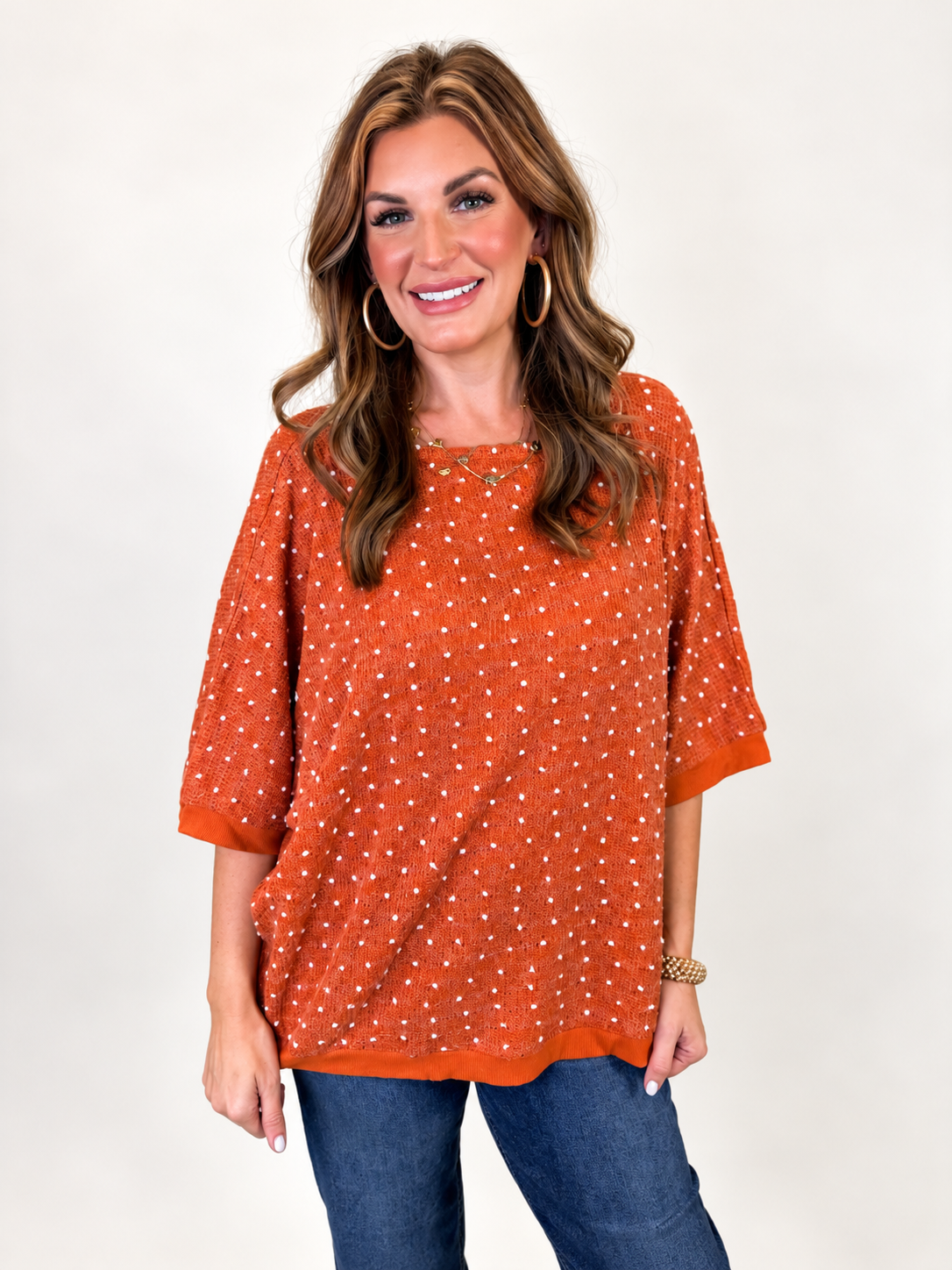 Close-up of Morgan wearing the Millie rust knit top, showing its textured dot design and wide sleeves.