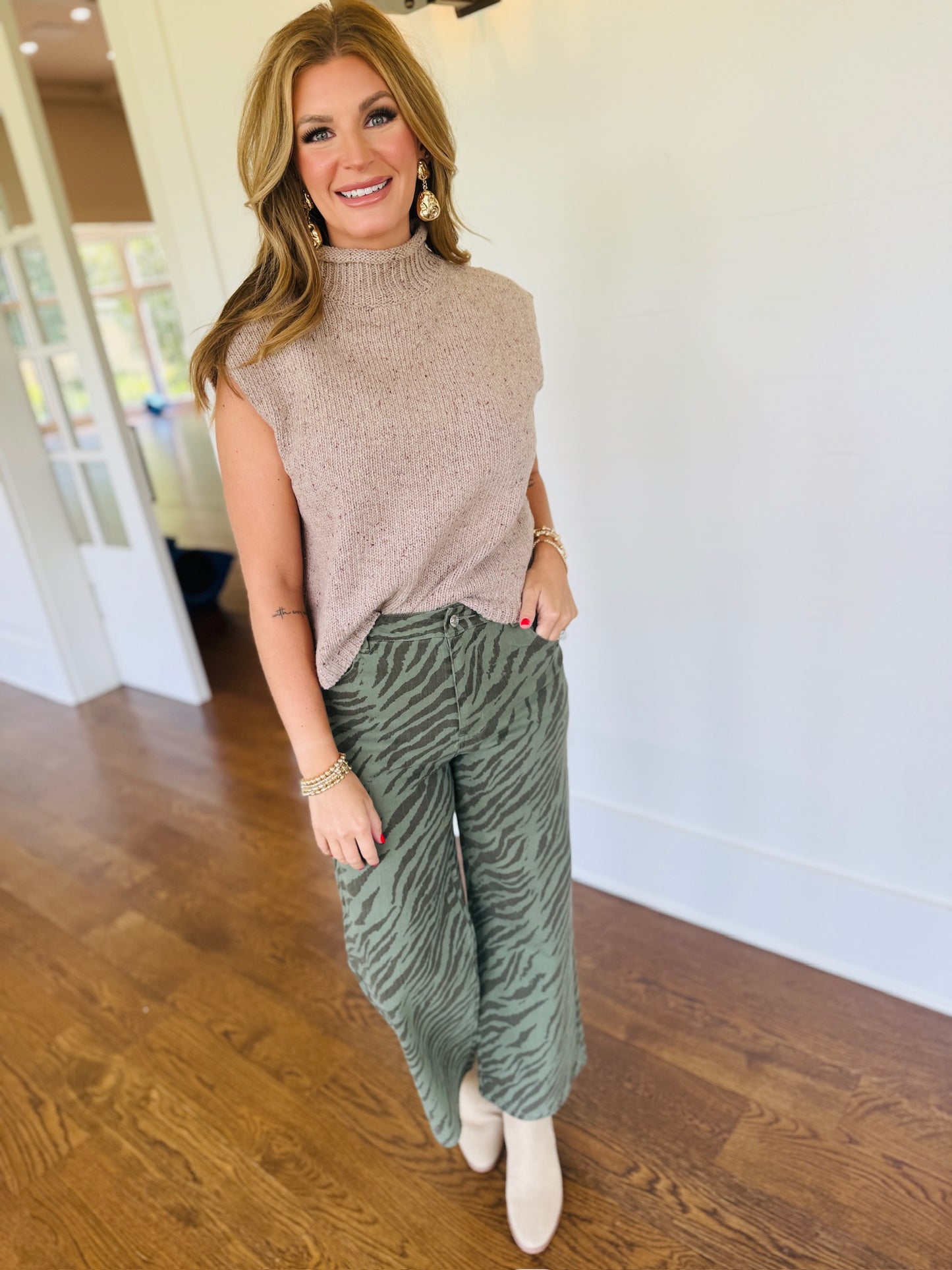 Morgan wearing the Nala taupe sleeveless mock-neck knit top with sage zebra-print pants and cream boots