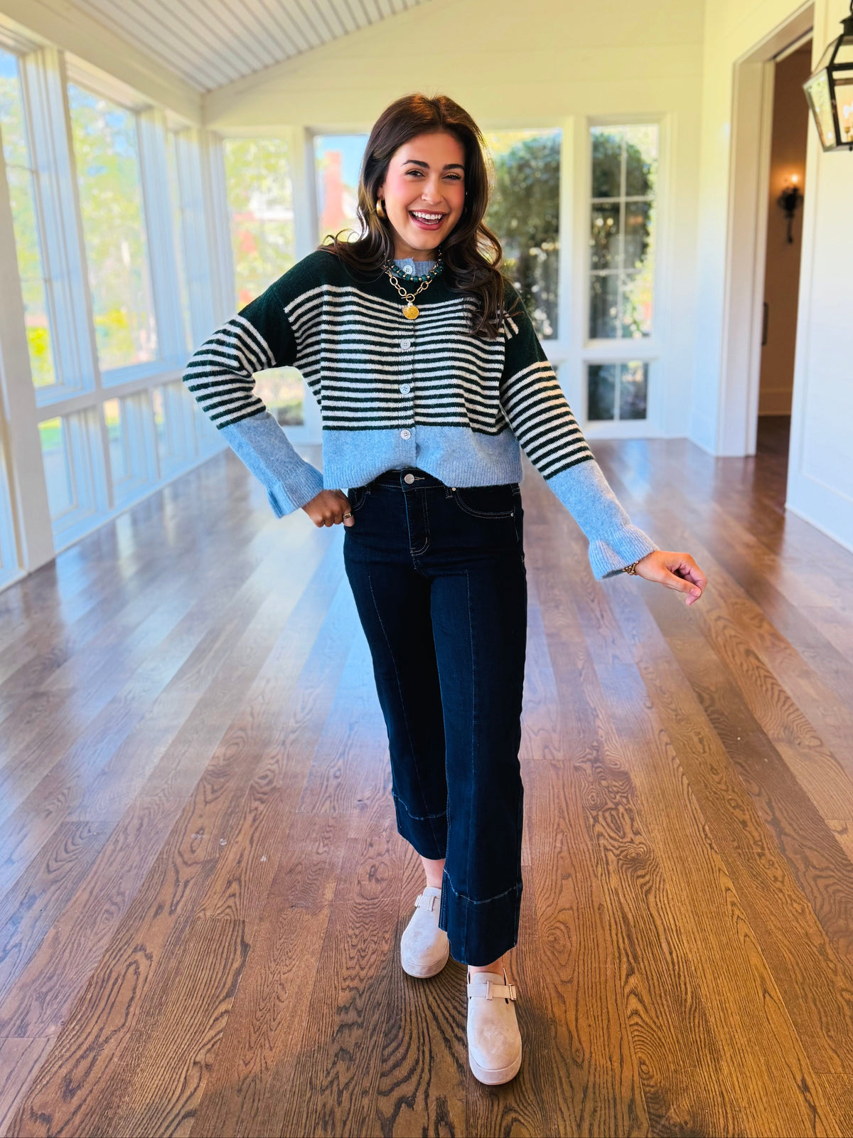Lacey wearing the Phoebe hunter green striped cardigan with dark cropped jeans and neutral flats.