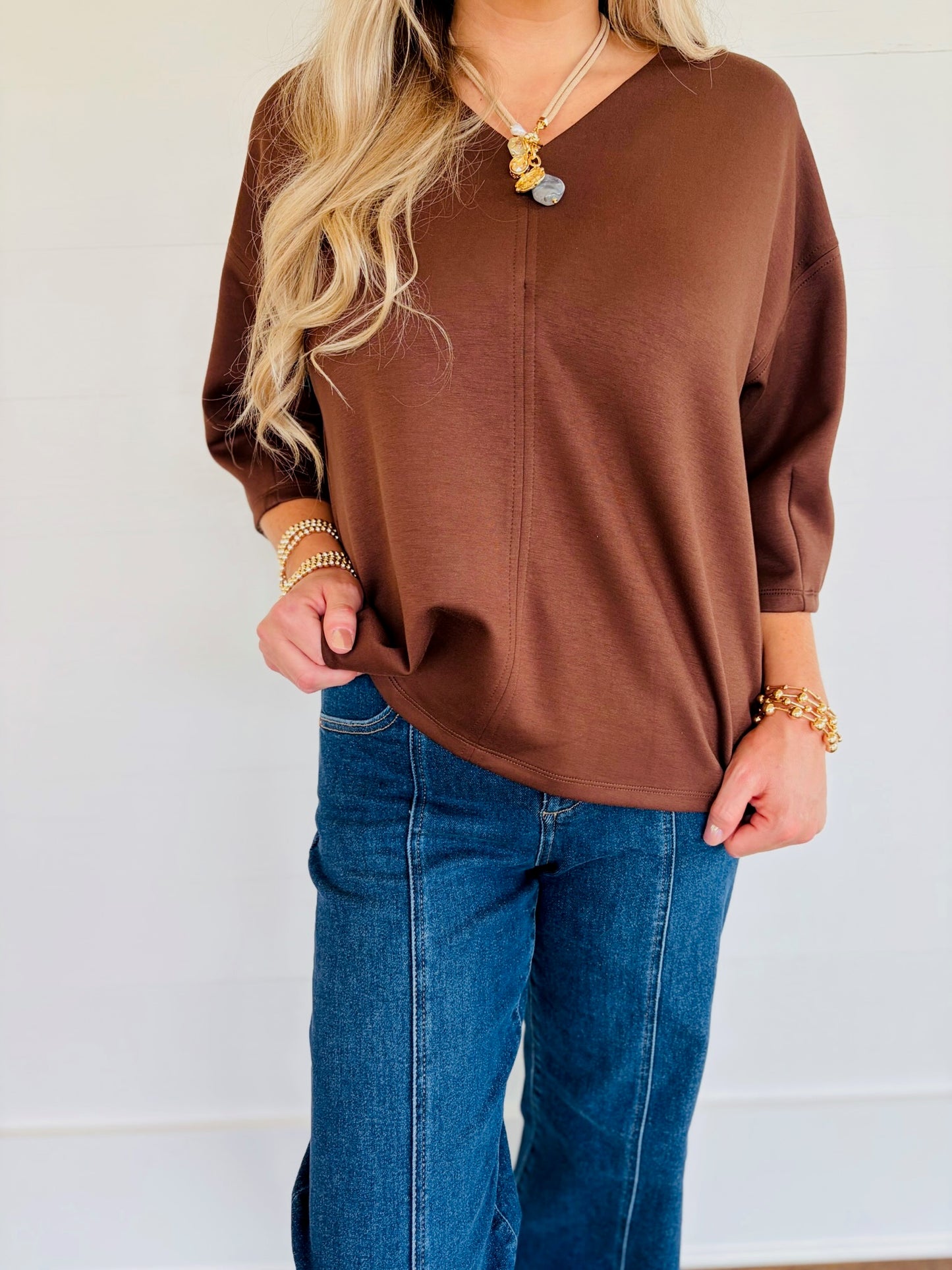 Close-up of Lorin wearing the Rosalie brown V-neck top with three-quarter sleeves and front seam detail