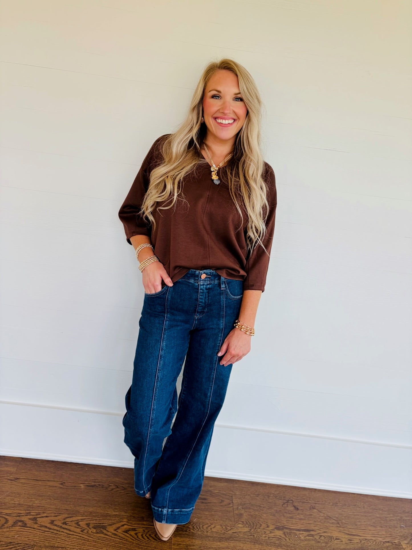 Lorin wearing the Rosalie brown V-neck top with three-quarter sleeves and blue wide-leg jeans