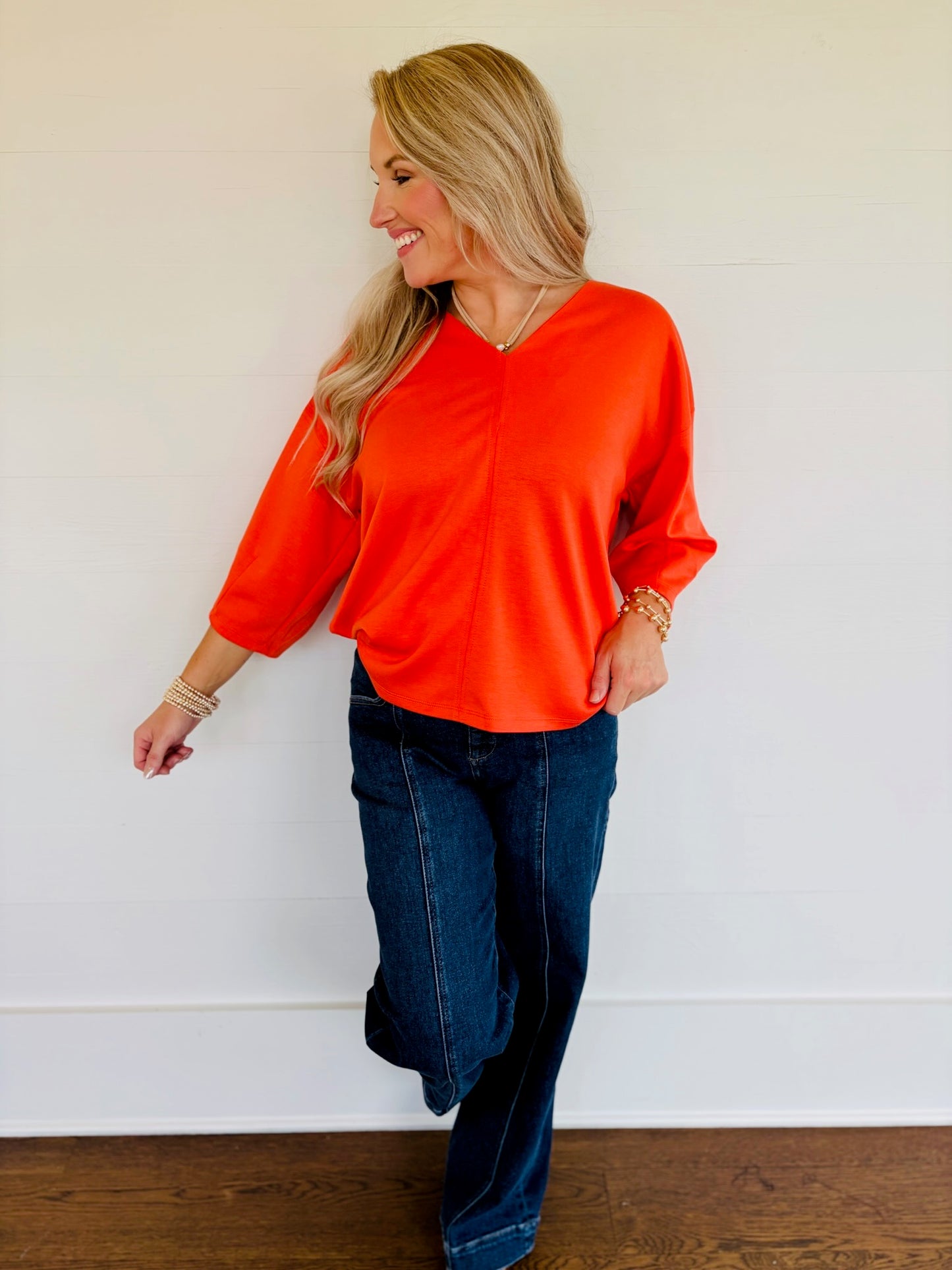 Lorin wearing the Rosalie terra cotta V-neck three-quarter-sleeve top with dark-wash wide-leg jeans