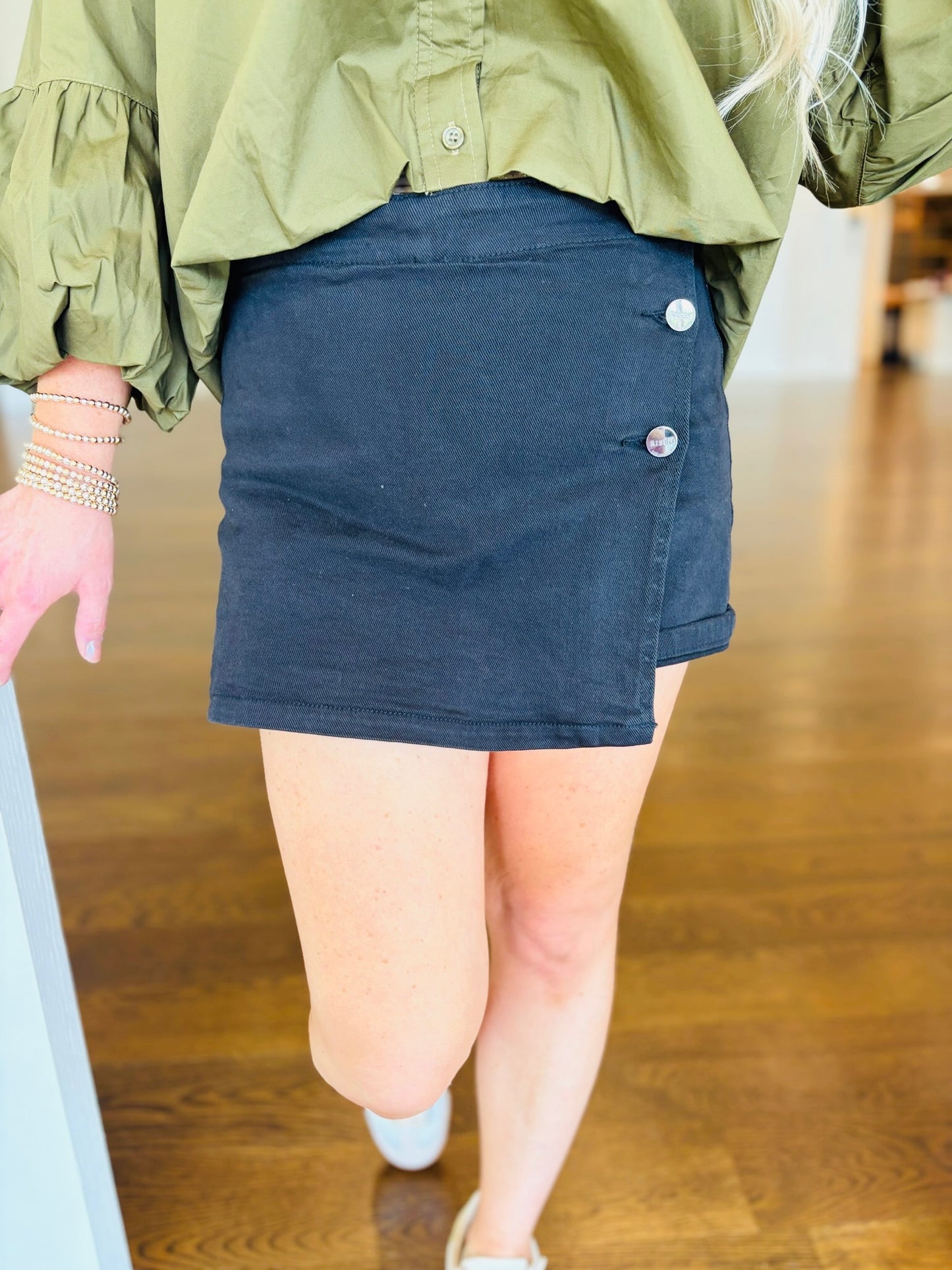 Close-up of the Sammy black wrap-front denim skort with silver-tone button details