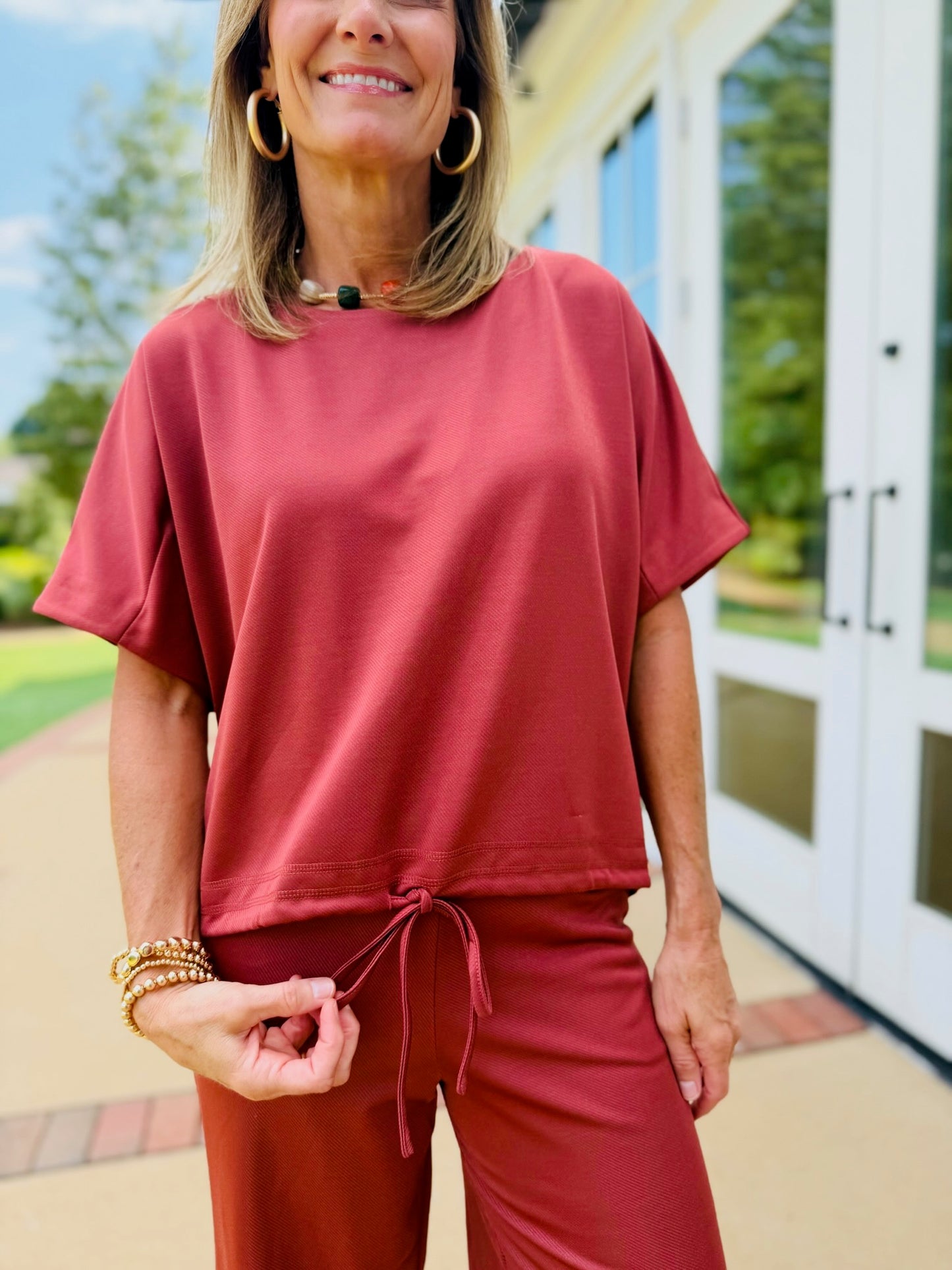 Full-length view of Ginny wearing the Sophia rust matching top and wide-leg pants set with cream heels