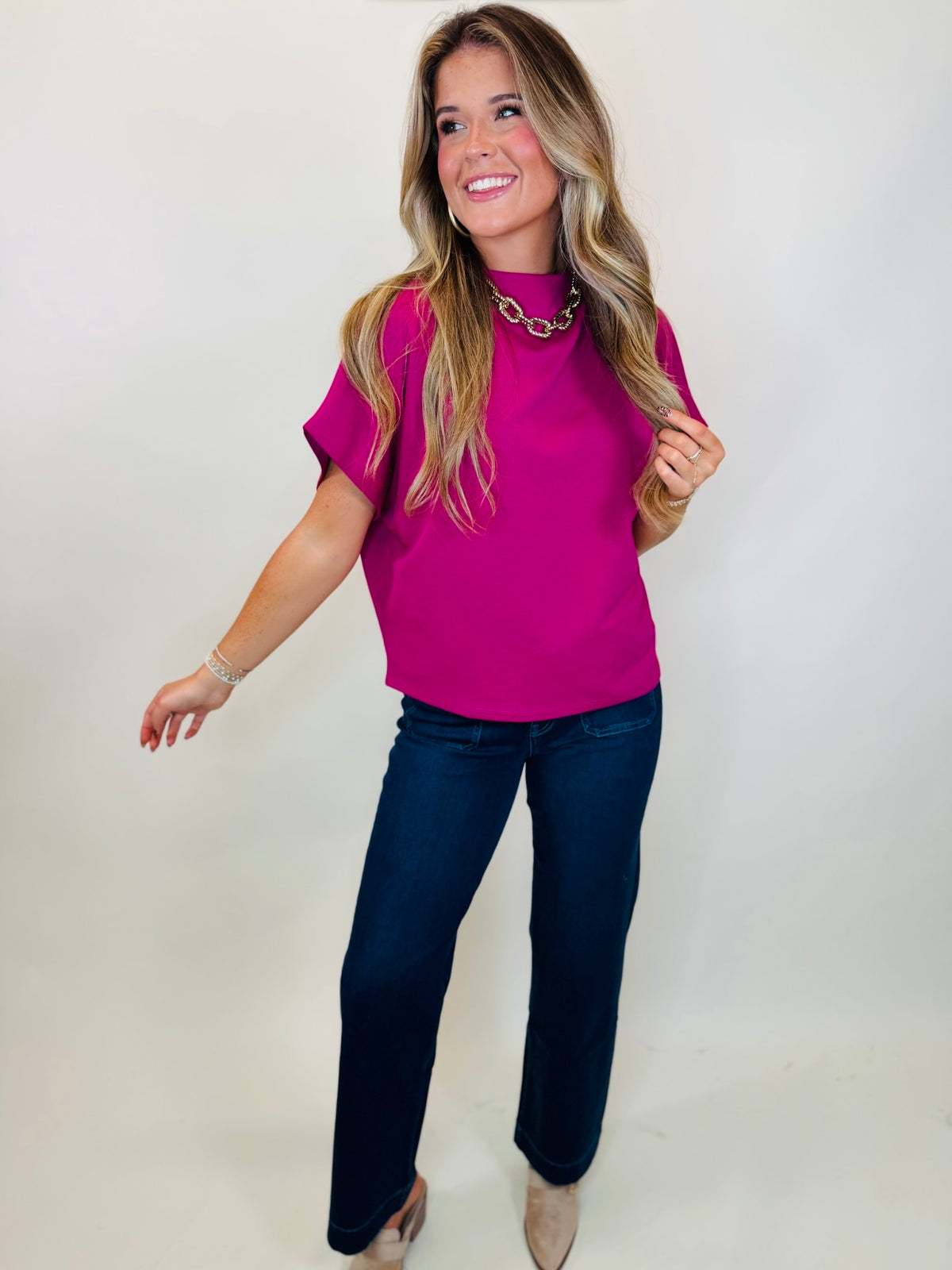 Sunrise magenta high neck blouse styled with Meagan dark wash jeans and beige heels.