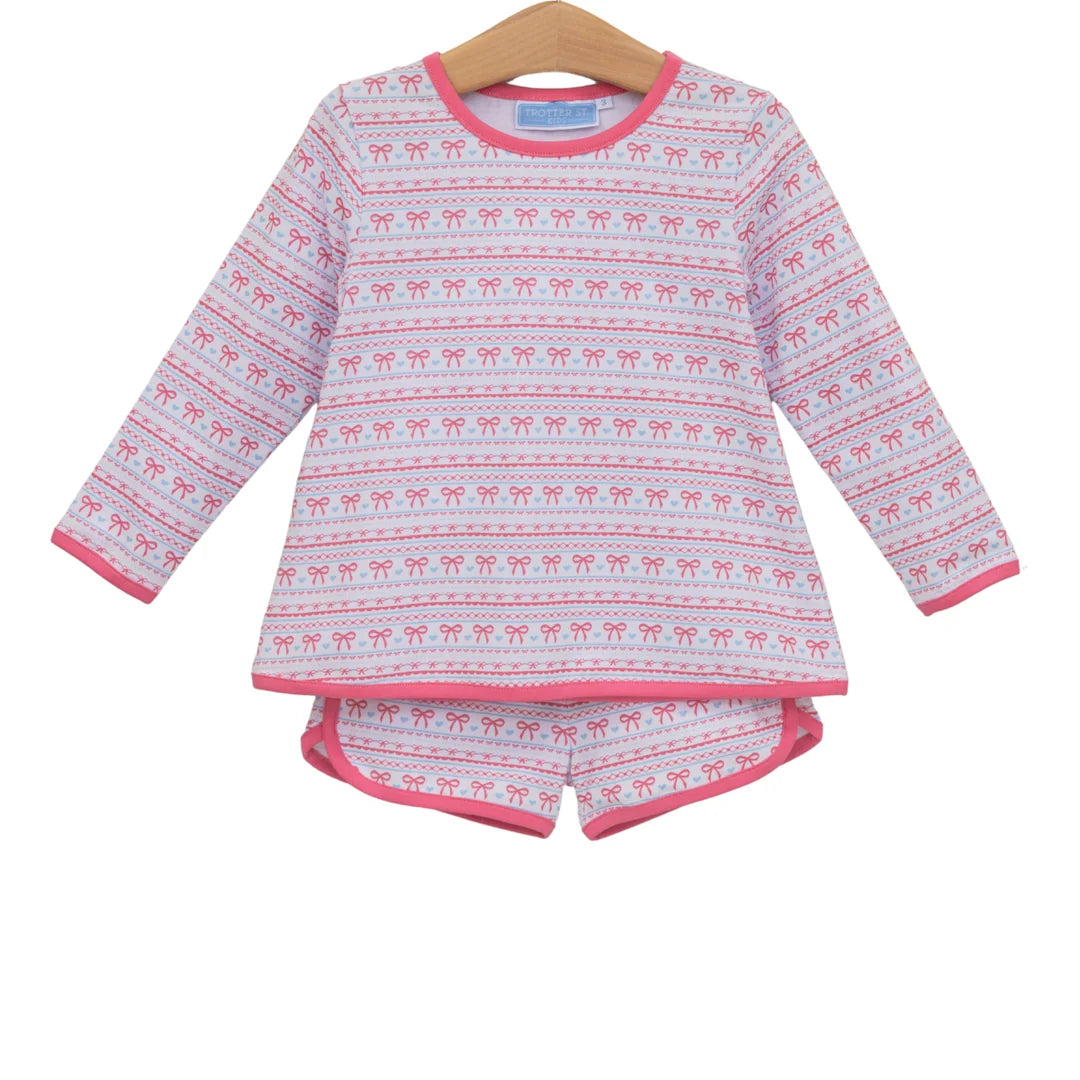 Children's pink and white long-sleeve top and shorts set with repeating bow pattern trim.