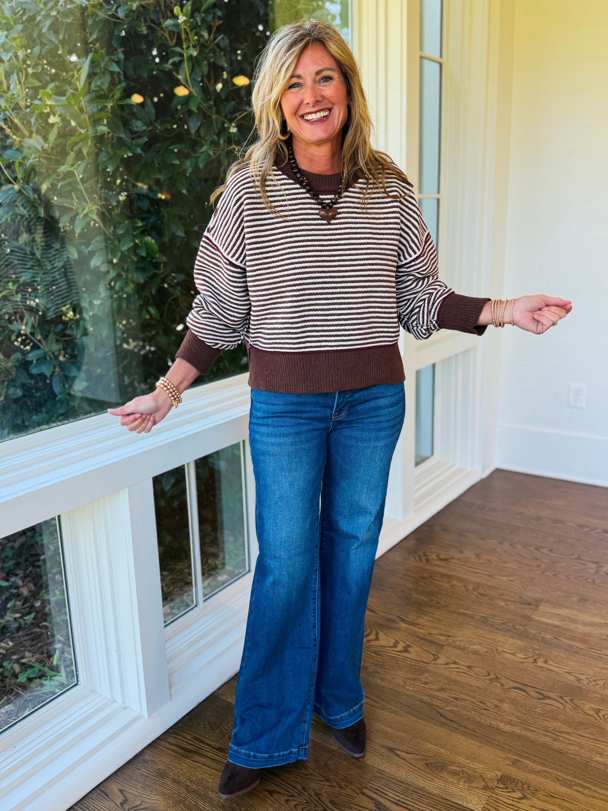 Kelly wearing the Tess chocolate striped split-hem sweater with blue wide-leg jeans and brown pointed-toe boots.