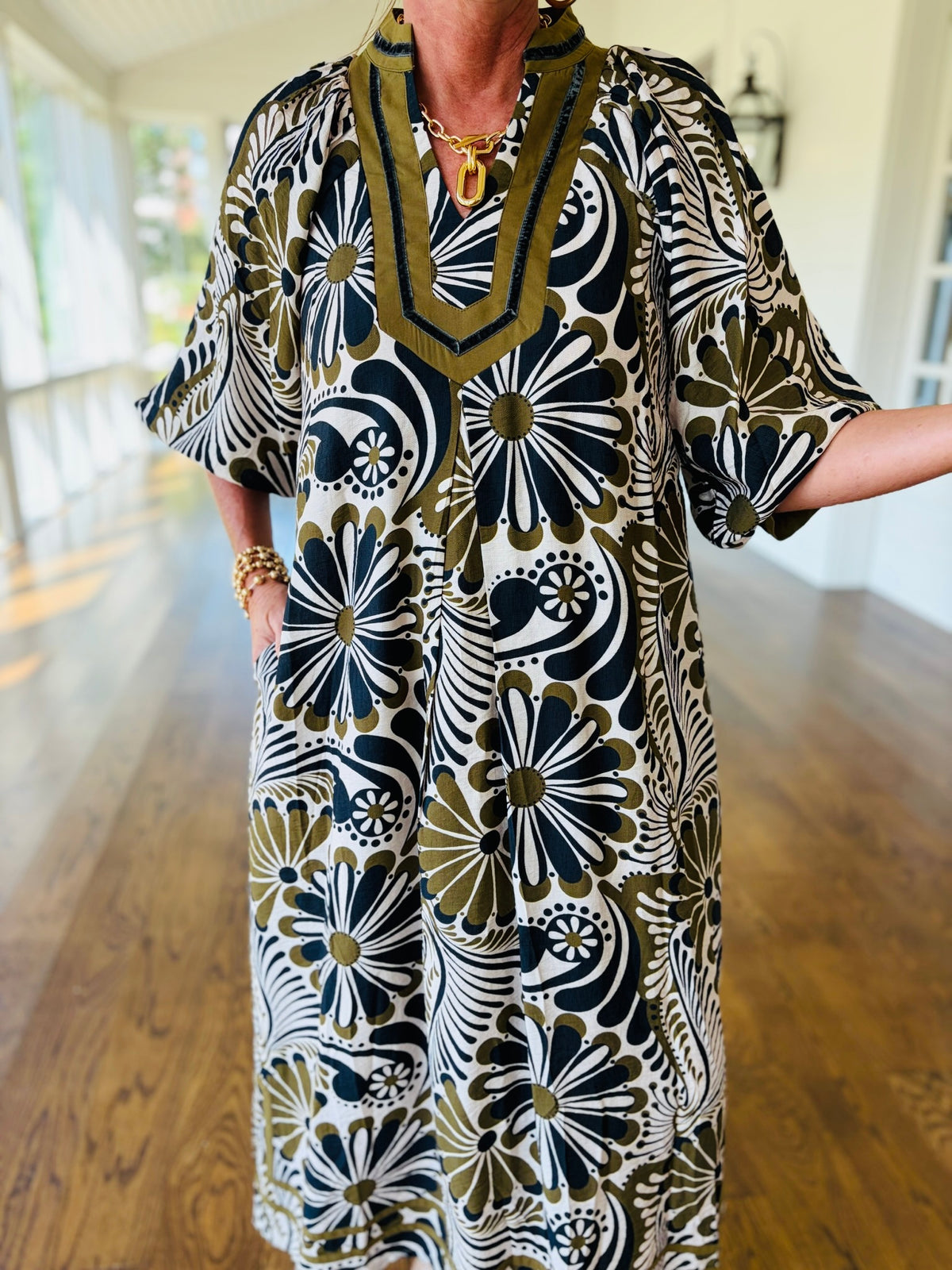 Close-up view of the embroidered split V-neckline and graphic floral pattern on The Magnolia caftan dress.