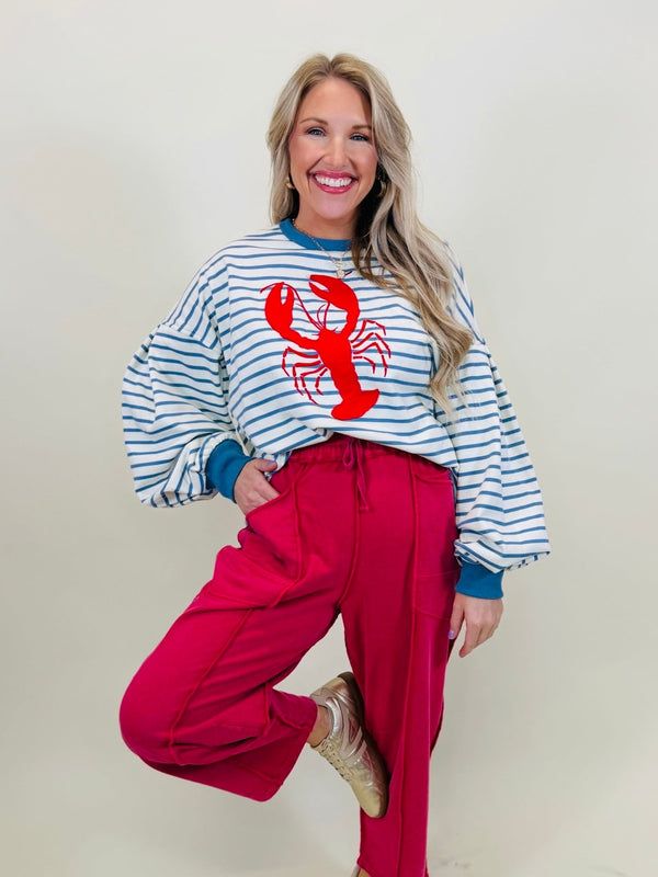 Lorin modeling The Palmer blue stripe lobster graphic pullover sweater with bright pink pants.