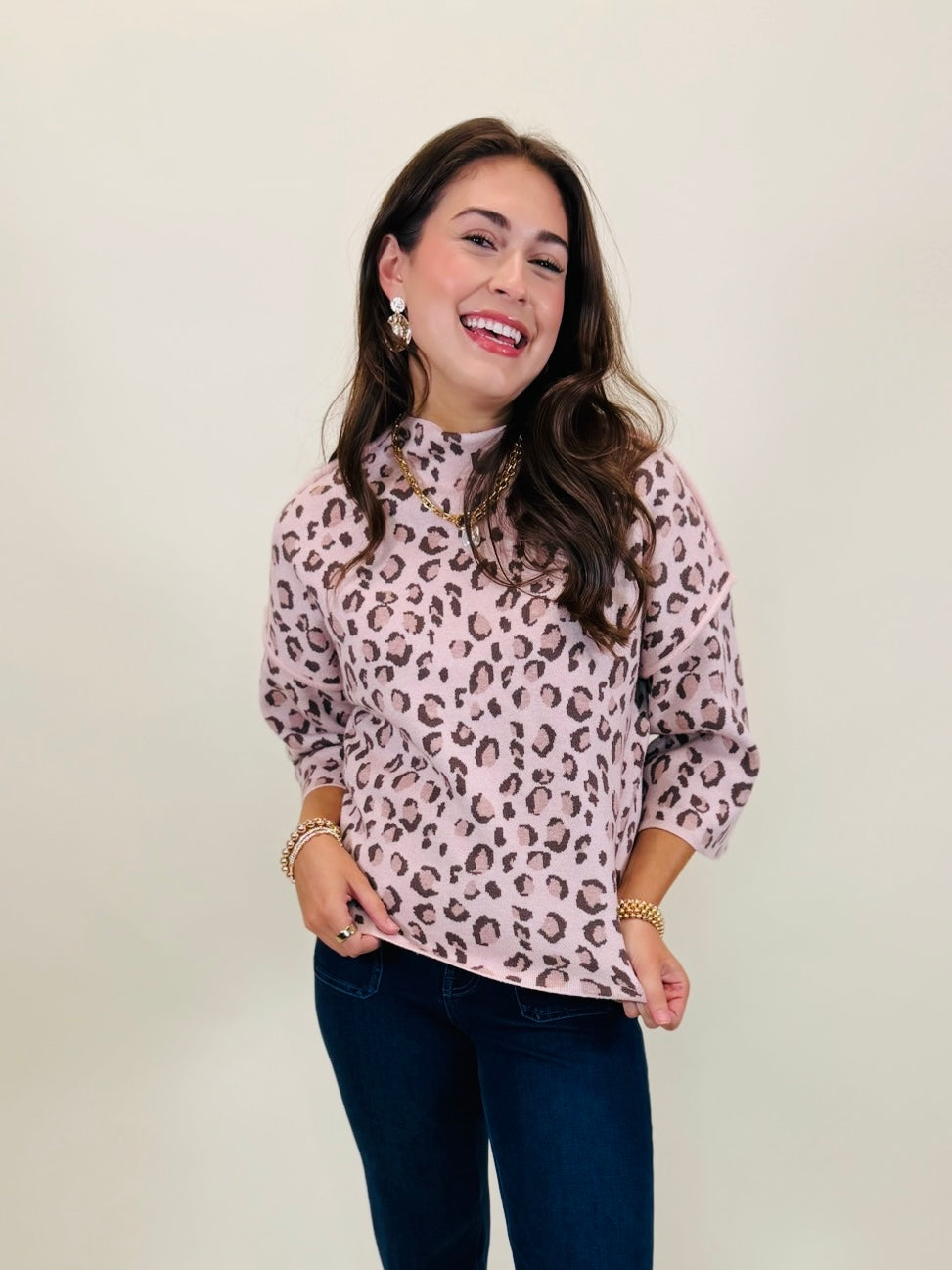Lacey modeling The Penelope light pink leopard print mock-neck top with dark blue jeans.