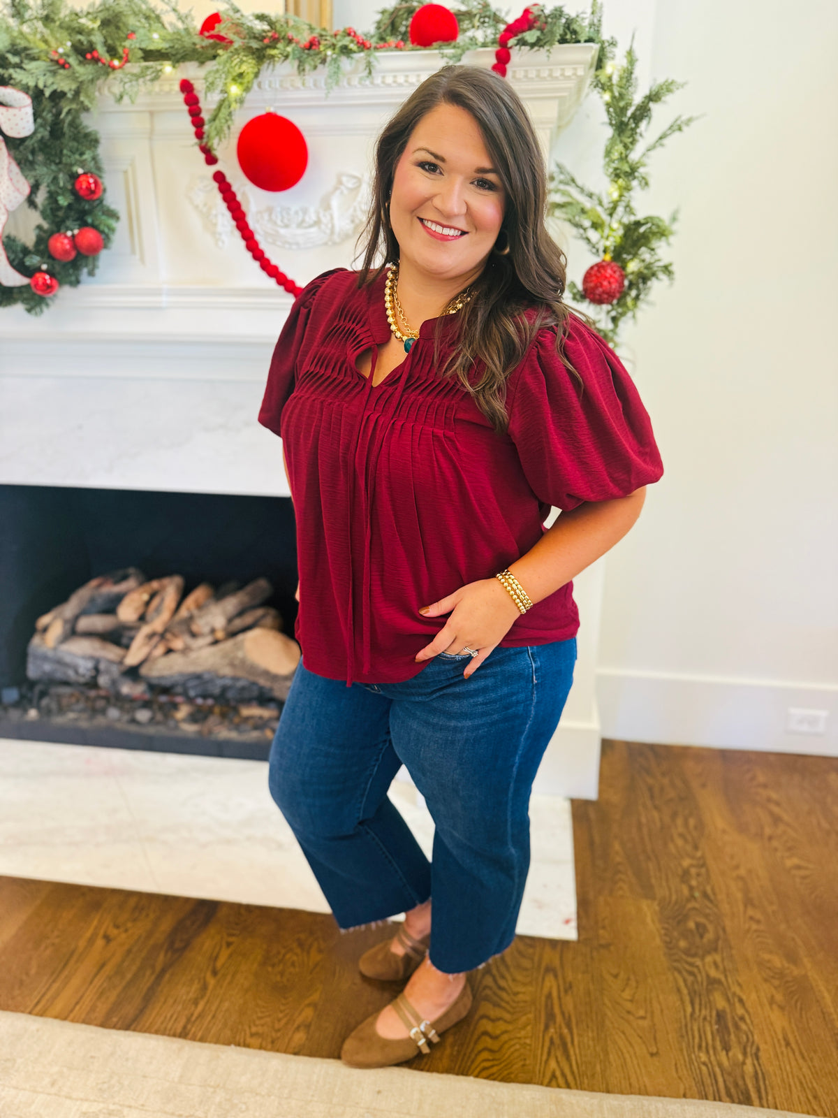 Model wearing the extended-size Vera burgundy pintuck blouse with blue jeans and brown flats.