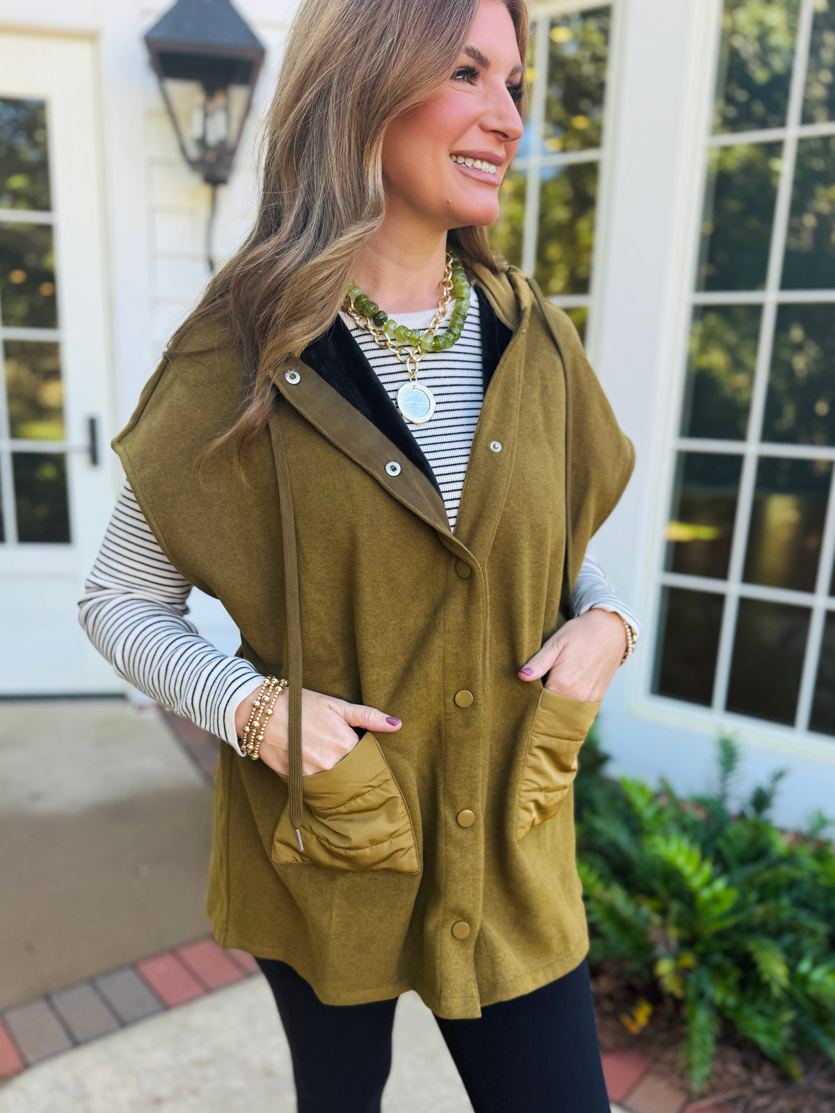 Morgan wearing the Veronica striped ribbed top beneath an olive hooded vest for a layered fall look.