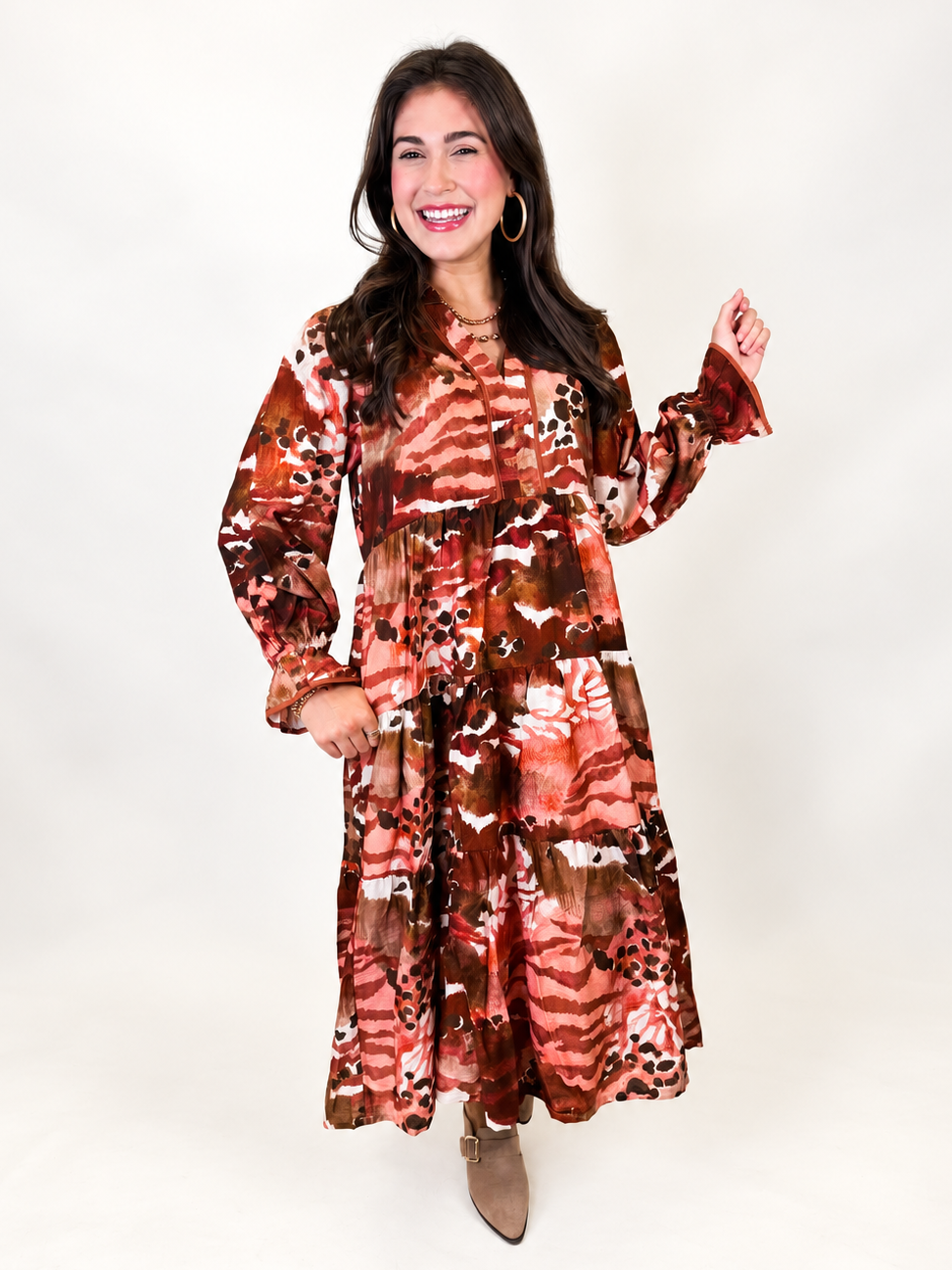 Lacey wearing the Victoria rust abstract print tiered midi dress with long balloon sleeves, a tie neckline and taupe ankle boots.