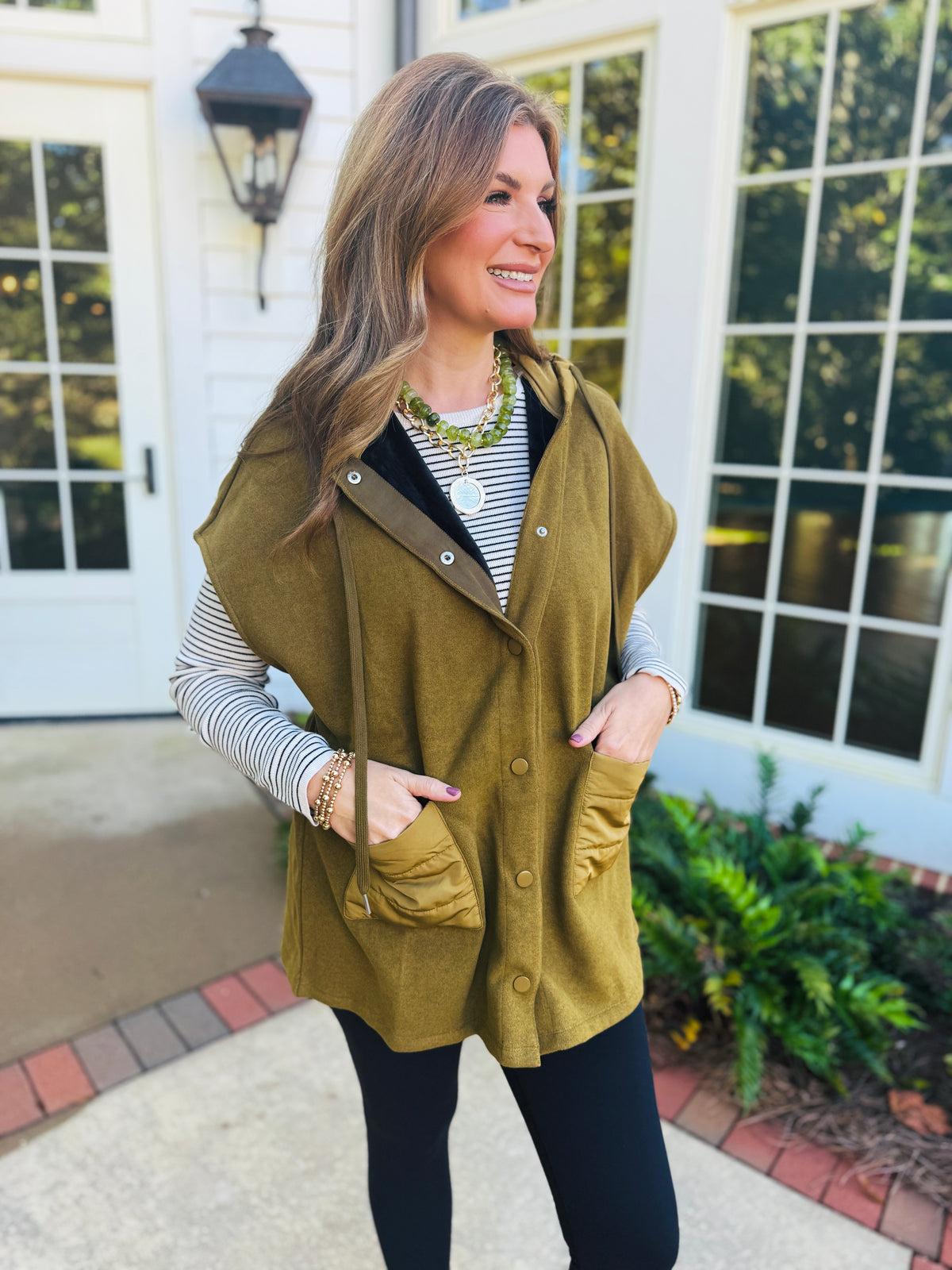 Morgan wearing the Winnie moss cinch-waist hooded jacket over a striped top with black leggings.